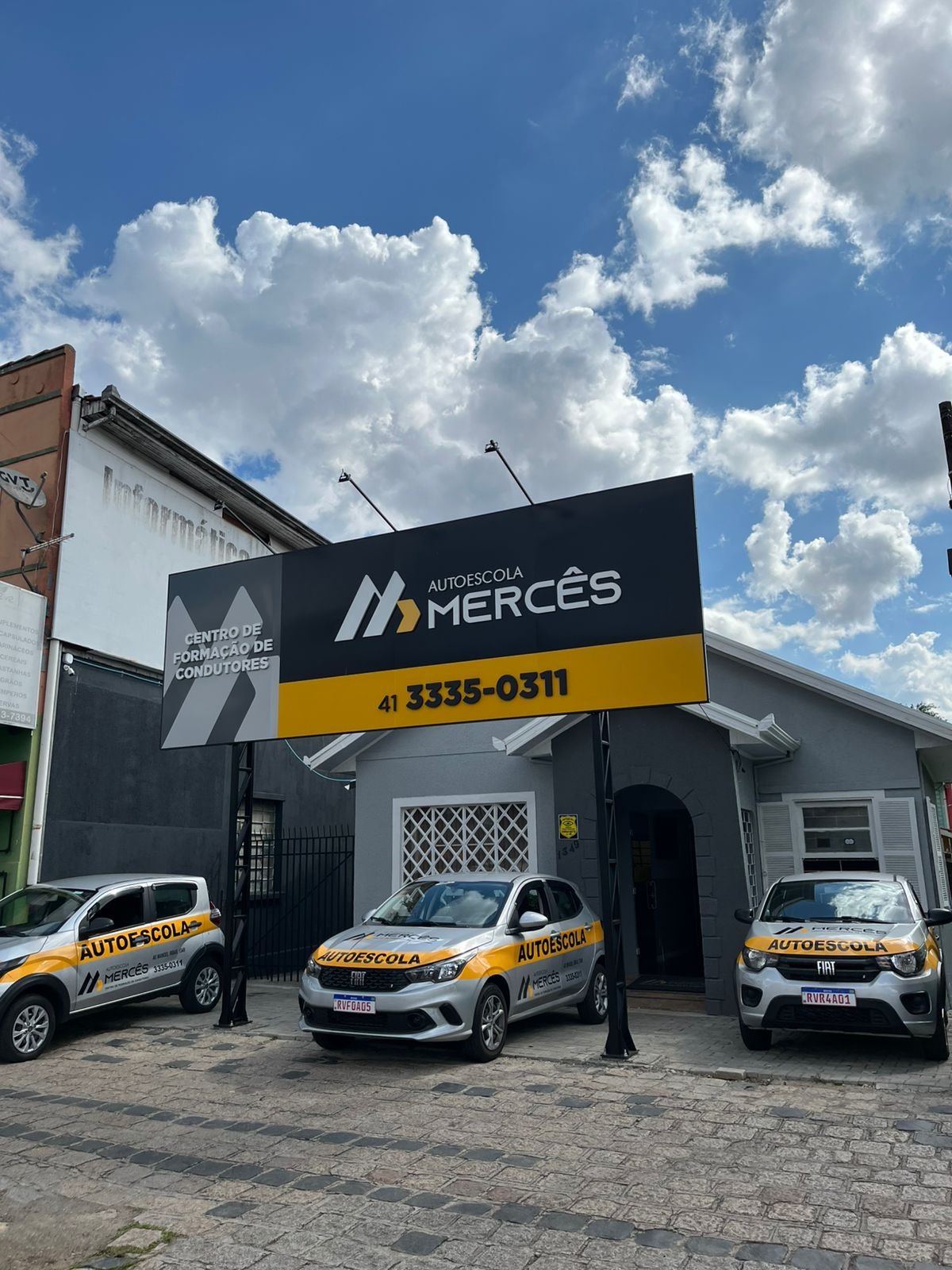 Fachada da Autoescola Mercês com carro de autoescola estacionado